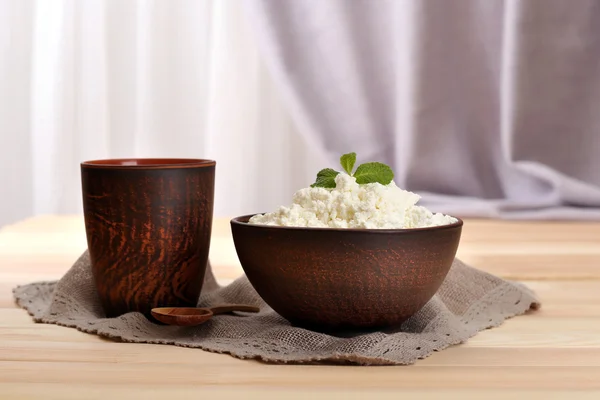 Cottage cheese in bowl with cup on table on fabric background — Stock Photo, Image