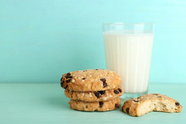 Tasty cookies and glass of milk on color wooden background — Stock Photo, Image