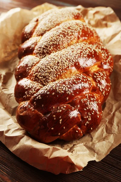 Frisches Brötchen auf Papier auf hölzernem Hintergrund — Stockfoto