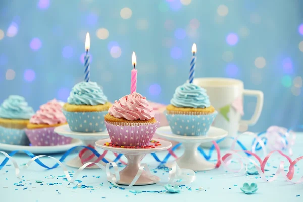 Deliciosos cupcakes en la mesa sobre fondo azul —  Fotos de Stock