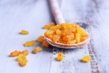 İçinde renk ahşap masa arka plan üzerine kaşık kuru üzüm