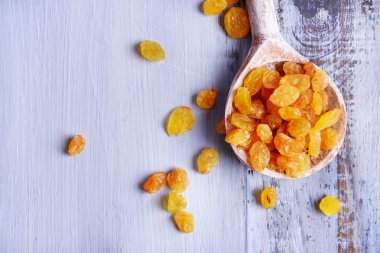 İçinde renk ahşap masa arka plan üzerine kaşık kuru üzüm