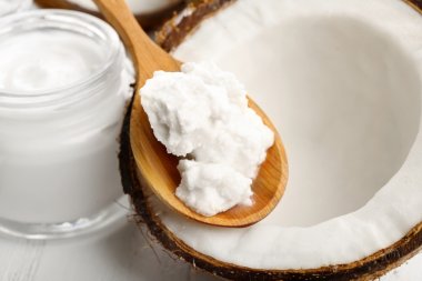 Coconut with coconut oil and jar of cosmetic cream on table close up clipart