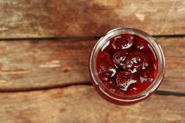 Kavanoz ahşap arka plan üzerinde çilek reçeli