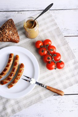 Ekmek ile plaka üzerinde ızgara sosis ve domates tablo üzerinde kapat