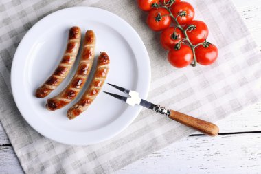 Plaka üzerinde ızgara sosis ve domates tablo üzerinde kapat