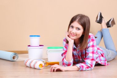 Güzel kız boyama duvar için ekipman ile yerde yatarken