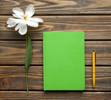 Defter ile ahşap arka plan üzerinde kalem ve Beyaz Lale