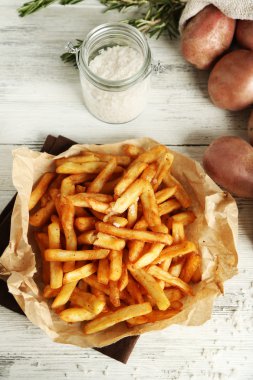 Ahşap masa arka plan üzerinde kağıt peçete üzerine lezzetli Fransız kızartması