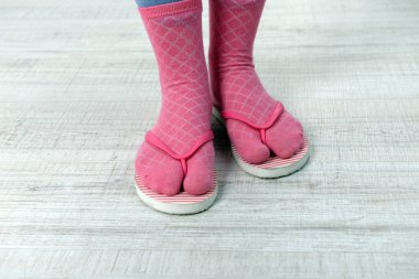 Kat zemin üzerine pembe parmak arası terlik ile çoraplı kadın ayakları