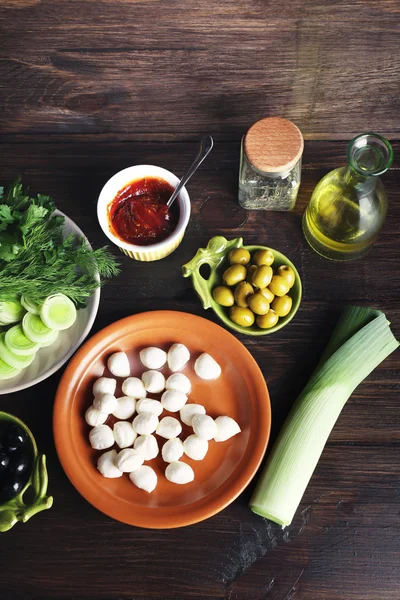 Queso mozzarella con aceitunas y verduras sobre fondo de madera — Foto de Stock