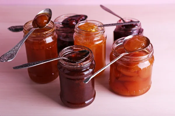 Jars of tasty jam on wooden background — Stock Photo, Image