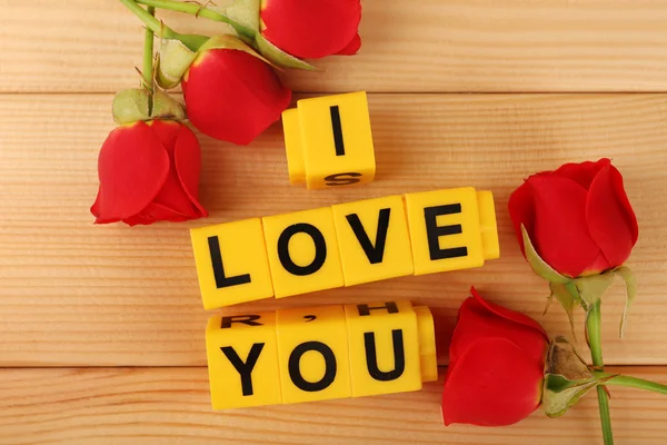 I Love You küpleri ahşap arka plan üzerinde çiçekler ile oluşan kelime — Stok fotoğraf