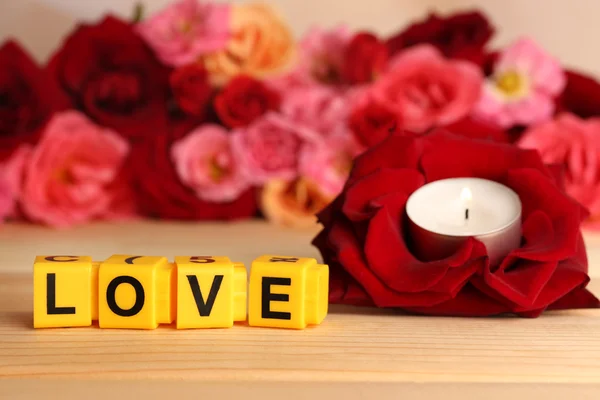 Letras decorativas formando palabra AMOR con flores y vela sobre fondo brillante —  Fotos de Stock