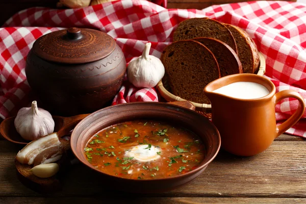 Ukrainian beetroot soup - borscht in bowl and pot, on napkin, on wooden background — Stock Photo, Image