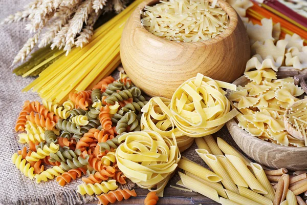 Diferentes tipos de pasta con trigo sobre fondo de mesa de madera —  Fotos de Stock