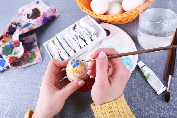 Peinture des œufs de Pâques par des mains féminines sur fond de nappe colorée — Photo