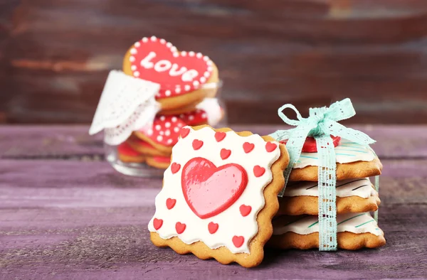 Hjärtformade kakor för alla hjärtans dag i glasburk på färg trä bakgrund — Stockfoto