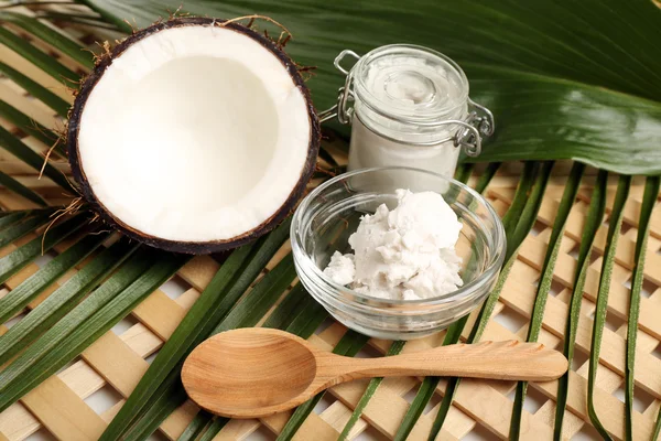 Cocco con foglie e olio di cocco in vaso su fondo di legno — Foto Stock