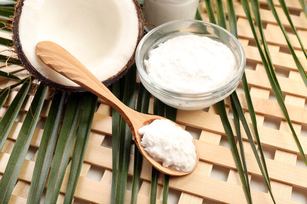 Coconut with leaf and coconut oil in bowl on wooden background