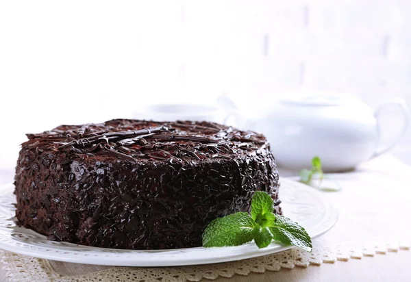 Sabroso pastel de chocolate con taza de té en la mesa de cerca —  Fotos de Stock