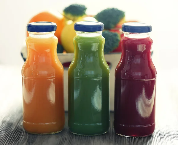 Bottles of juice with fruits and vegetables on table close up — Stock Photo, Image