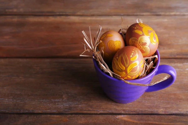 Œufs de Pâques en tasse sur fond en bois — Photo