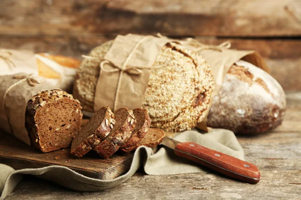 Verschillende vers brood, op oude houten tafel — Stockfoto