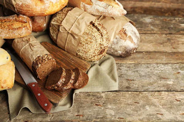 Different fresh bread, on old wooden table — Stock Photo, Image