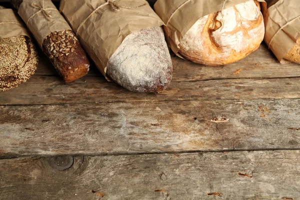 Different fresh bread, on old wooden table — Stock Photo, Image