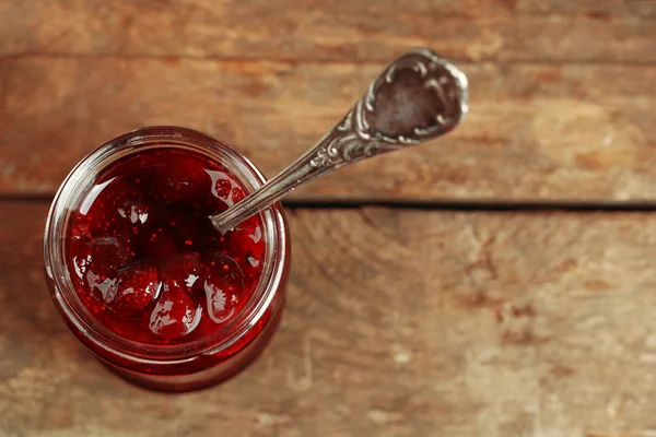 Pot aardbeienjam met lepel op houten achtergrond — Stockfoto