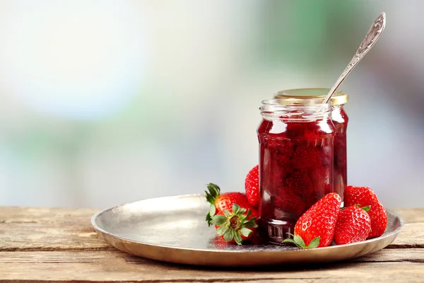 Pot aardbeienjam met bessen op tafel op lichte achtergrond — Stockfoto