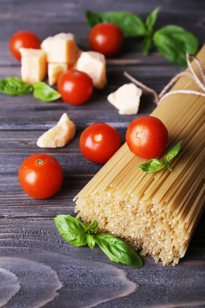 Pastas crudas con tomates y queso sobre fondo de madera —  Fotos de Stock