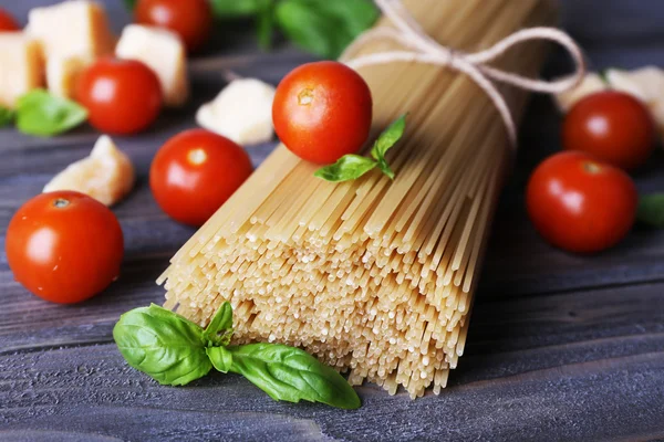 Ruwe pasta met tomaten en kaas op houten achtergrond — Stockfoto