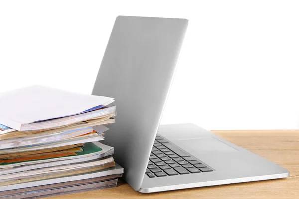 Laptop and stack of magazines on table isolated on white — Stock Photo, Image