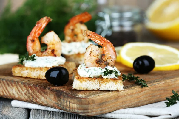 Appetizer canapé com camarão e limão na tábua de corte na mesa de perto — Fotografia de Stock