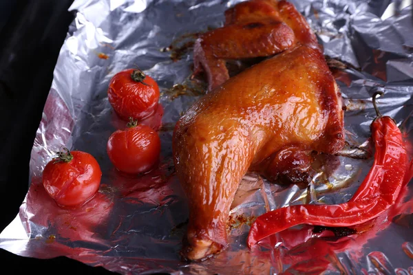 Smoked chicken leg with cherry tomatoes on foil close up — Stock Photo, Image