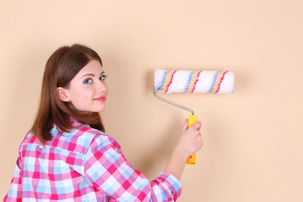 Hermosa mujer pinta la pared en la habitación —  Fotos de Stock