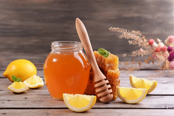 Вкусный мед с лимоном на столе на деревянном фоне — стоковое фото
