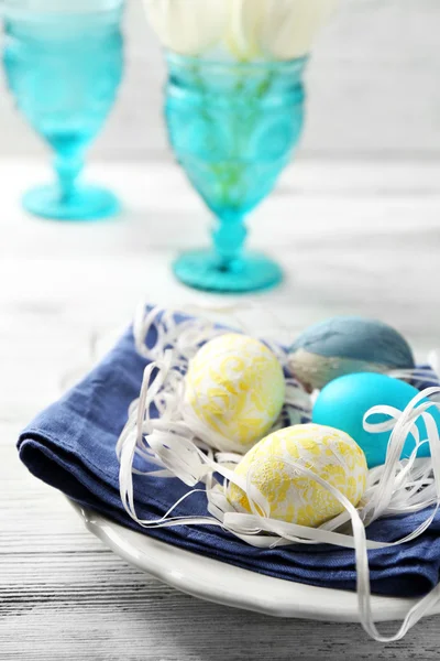 Osterkomposition mit bunten Eiern auf Tellern auf hölzernem Tischhintergrund — Stockfoto