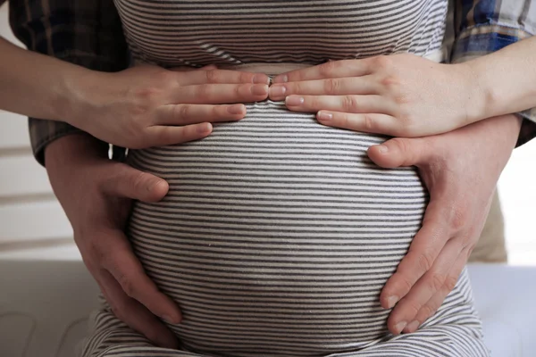 Молода вагітна жінка з чоловіком торкається живота крупним планом — стокове фото