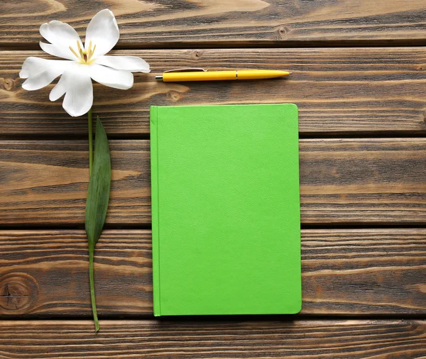 Ноутбук с ручкой и белым тюльпаном на деревянном фоне — стоковое фото