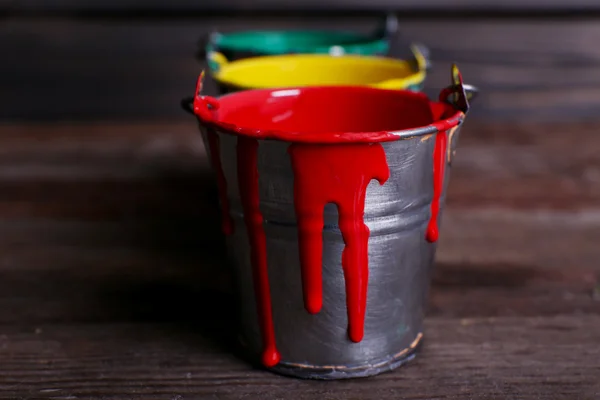 Metalowe wiaderka z kolorowe farby na drewniane tła — Zdjęcie stockowe