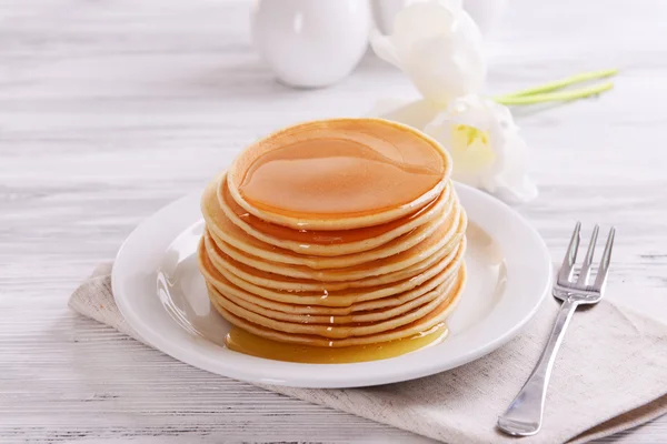 Deliciosos panqueques con miel en el plato en primer plano de la mesa — Foto de Stock