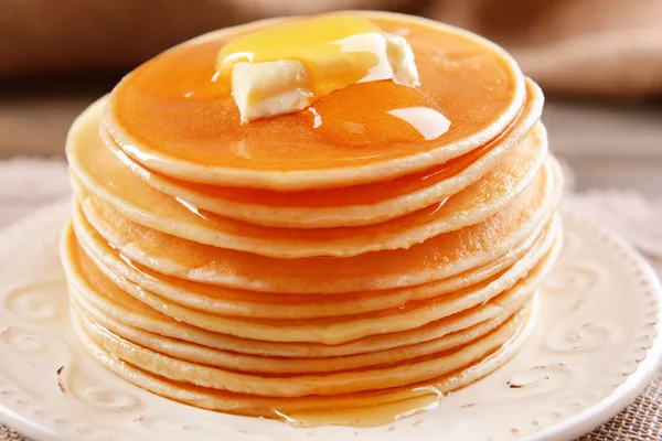 Deliciosos panqueques con miel en el plato en primer plano de la mesa — Foto de Stock