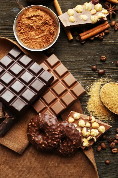 Still life with set of chocolate, nuts and spices on wooden table, top view — Stock Photo, Image