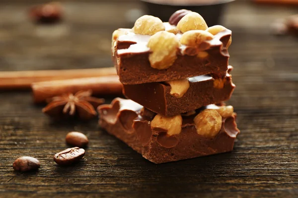 Tumpukan cokelat dengan kacang di atas meja kayu, closeup — Stok Foto