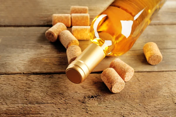 Glass bottle of wine with corks on wooden table background — Stock Photo, Image