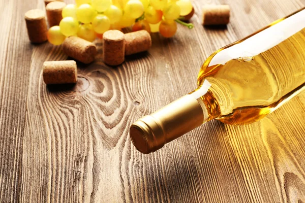 Ahşap masa arkasında mantarlı cam şarap şişesi.