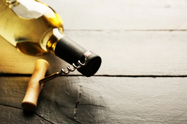 Glass bottle of wine with corkscrew on wooden table background — Stock Photo, Image